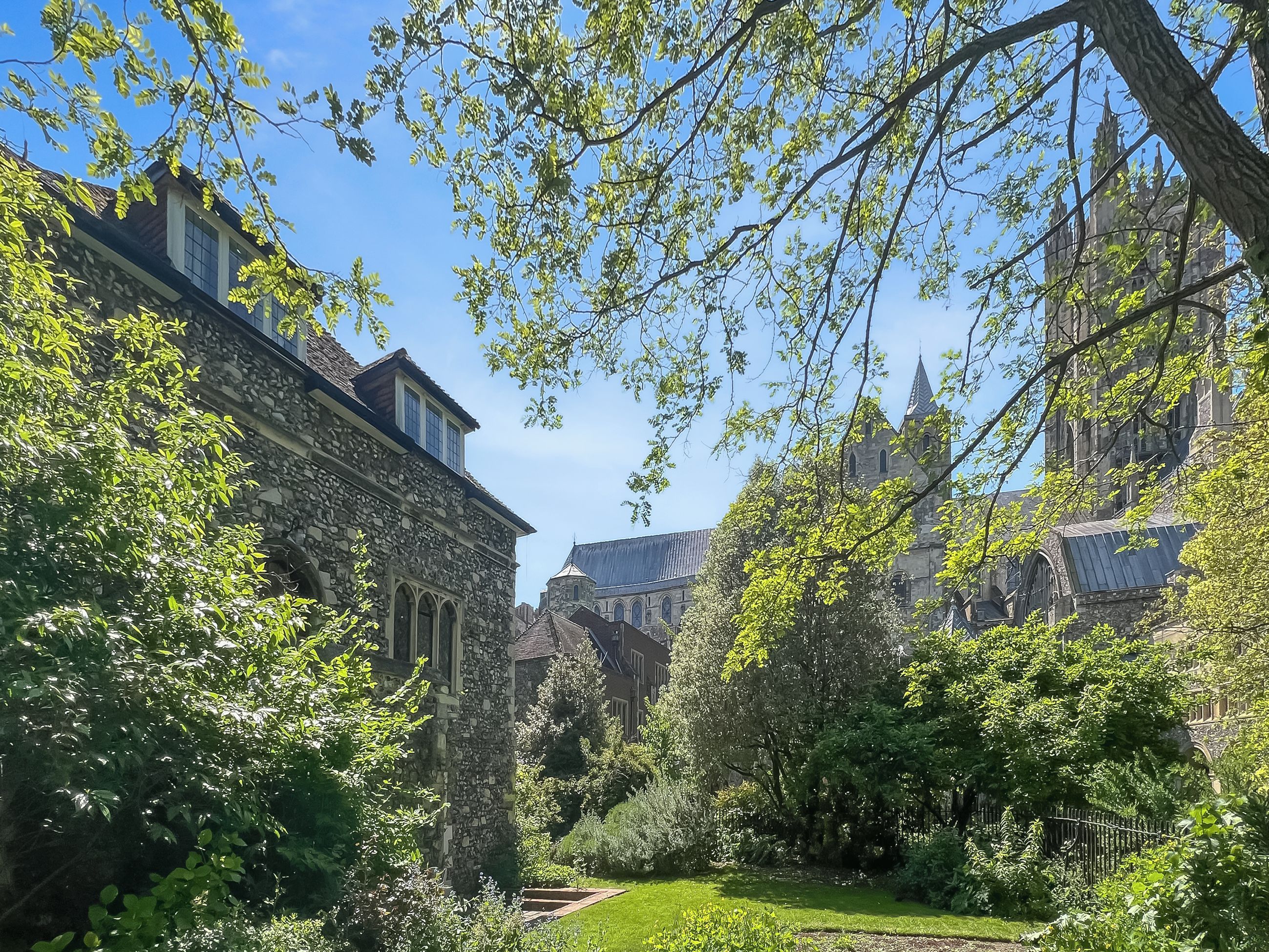 A historic building with stone architecture, surrounded by lush greenery and a well-maintained garden.