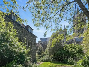 Un bâtiment historique à l’architecture de pierre, entouré d’une végétation luxuriante et d’un jardin bien entretenu.