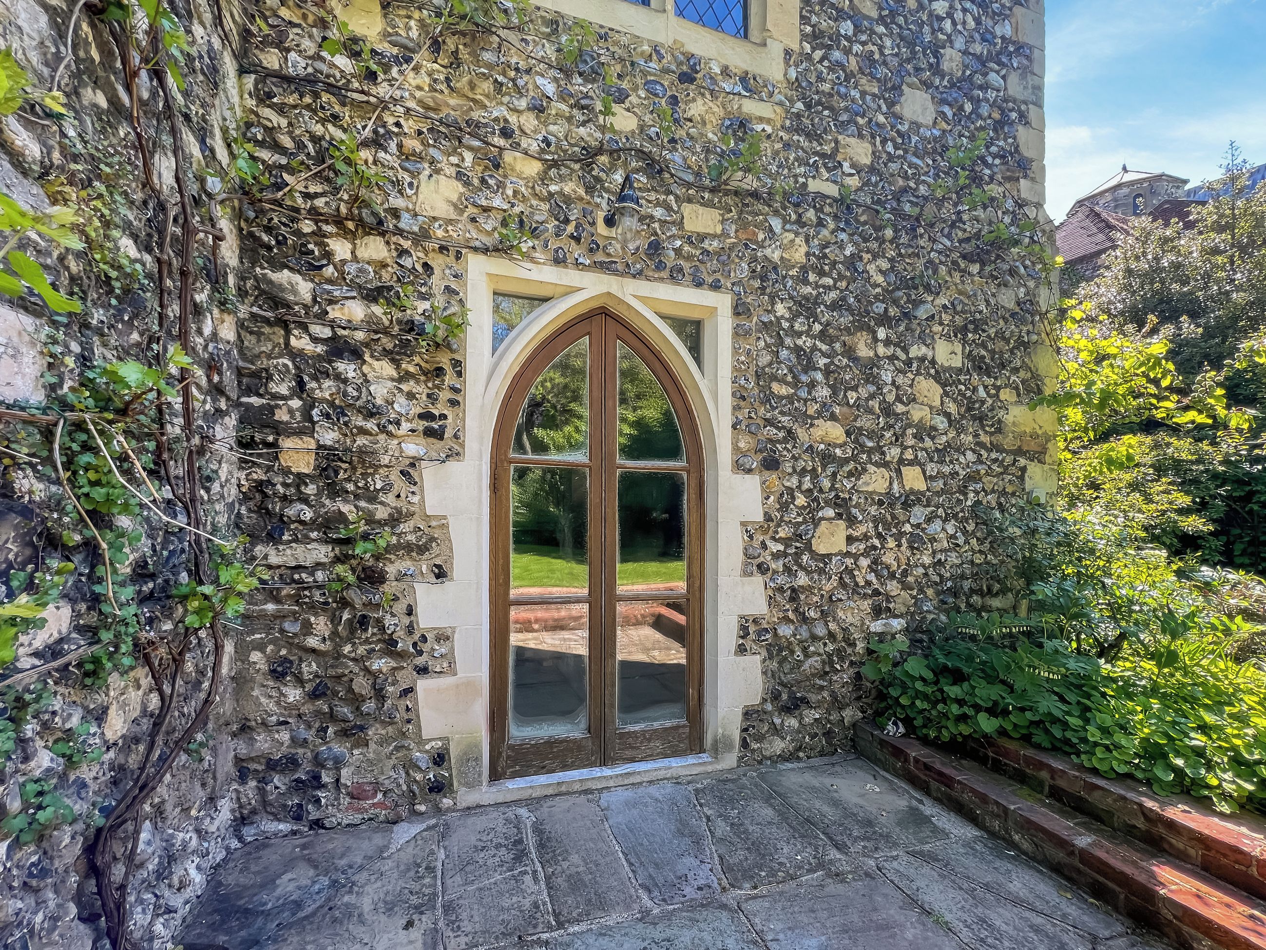 A stone building with a large arched window and a stone staircase leading to a door.