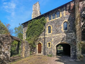 Un bâtiment en pierre doté de fenêtres en arc de cercle et d’une porte en bois.