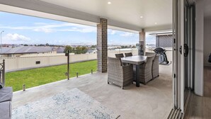 A covered patio area with a dining table and chairs, a grill, and a view of the surrounding neighborhood. - Ignatius Retreat | Bathurst | Family Entertainer (Kelso)
