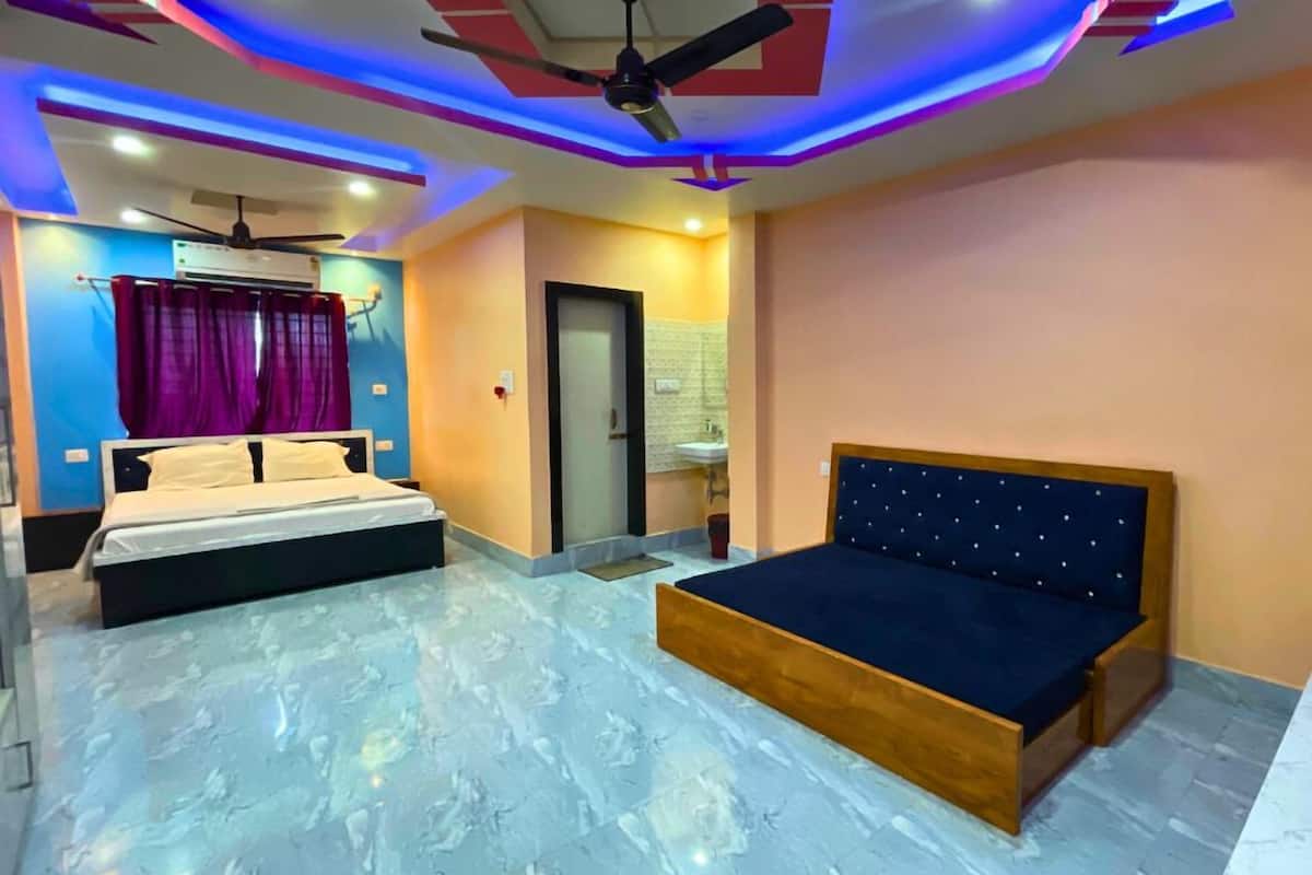 A bedroom with a bed, a ceiling fan, and a bathroom with a sink and mirror.