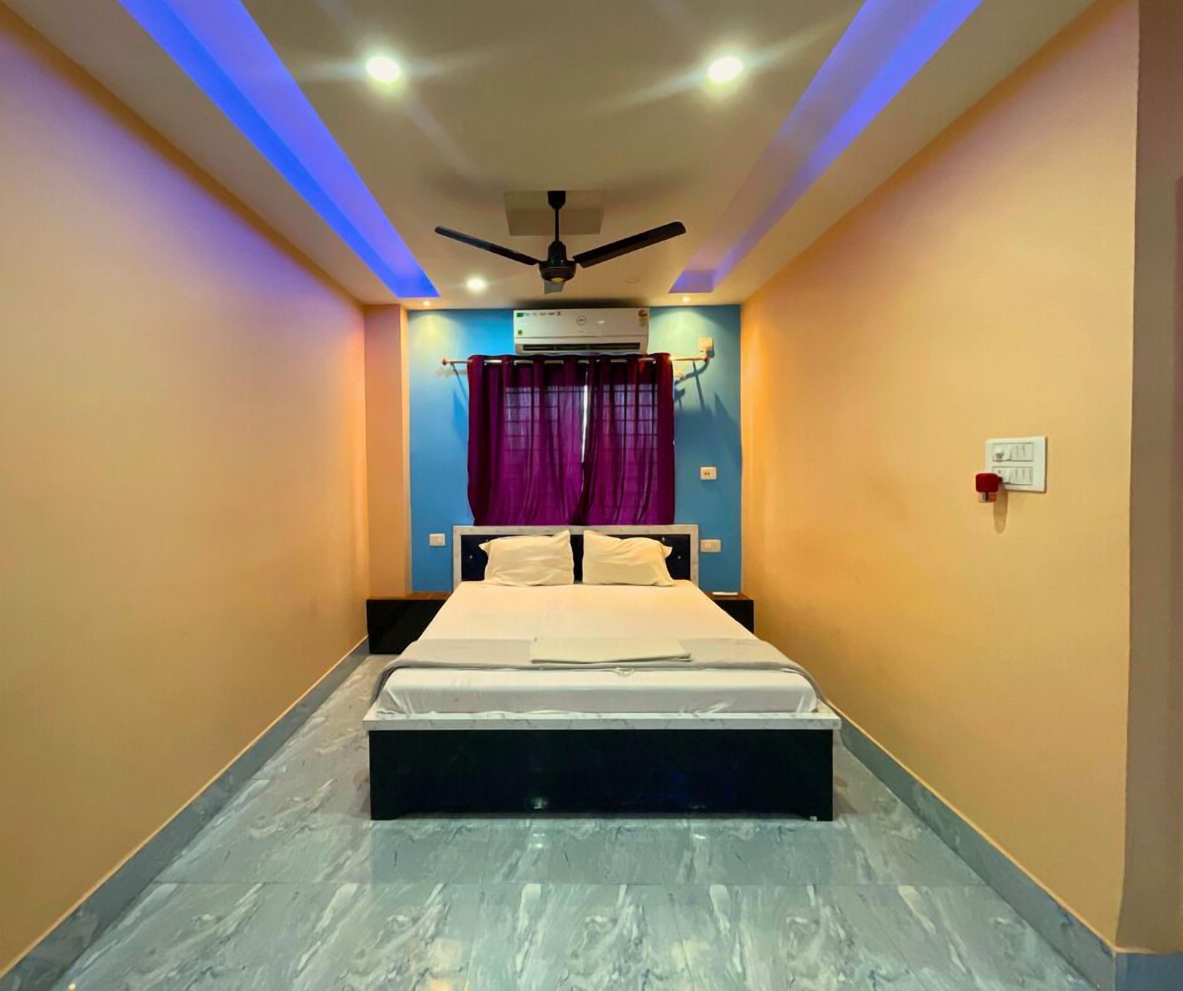 Un dormitorio con cama, ventilador de techo, aire acondicionado y cortinas moradas.