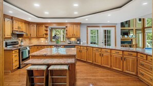A spacious kitchen with wooden cabinets, a granite countertop, and a large window. - Freele Escape | Hot Tub | Nature Lovers Dream! (Priddis)