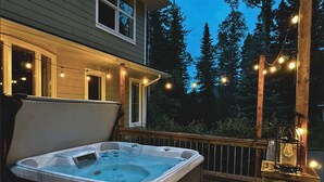 A hot tub on a wooden deck with string lights, surrounded by trees. - Freele Escape | Hot Tub | Nature Lovers Dream! (Priddis)