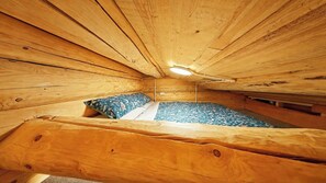 A wooden interior with a bed, pillows, and a ceiling light.