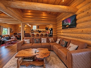 A log cabin interior with a large wooden sofa, a unique coffee table, and a painting of a forest scene. - Grand Country Estate 3 Hot Tubs Sleeps 16 near Durham City & Bishop Auckland (Oakenshaw)