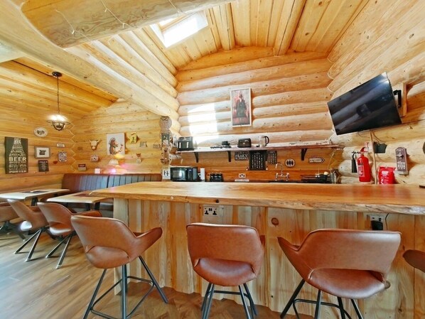 Eine Holzhütte mit Bar, Sitzgelegenheiten und einer Küche.