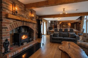 A cozy living room with a brick fireplace, a wooden coffee table, and a sofa. - Grand Country Estate 3 Hot Tubs Sleeps 16 near Durham City & Bishop Auckland (Oakenshaw)
