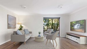 A modern living room with a grey sofa, a coffee table, and a TV on a wooden stand.