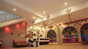 A reception area with a sofa, a desk, and a staircase. - Hotel Golden Bird (Pushkar)