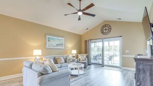 A spacious living room with a grey sectional sofa, a round coffee table, and a ceiling fan.