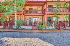 A multi-story building with wooden balconies, a central staircase, and a gravel driveway. - Hike, Bike & Ski: Red River Condo w/ Spa Access (Red River)