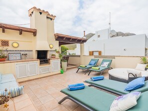 An outdoor patio with a barbecue area, lounge chairs, and a small pool.