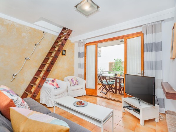 A living room with a sofa, a coffee table, a TV, and a staircase.