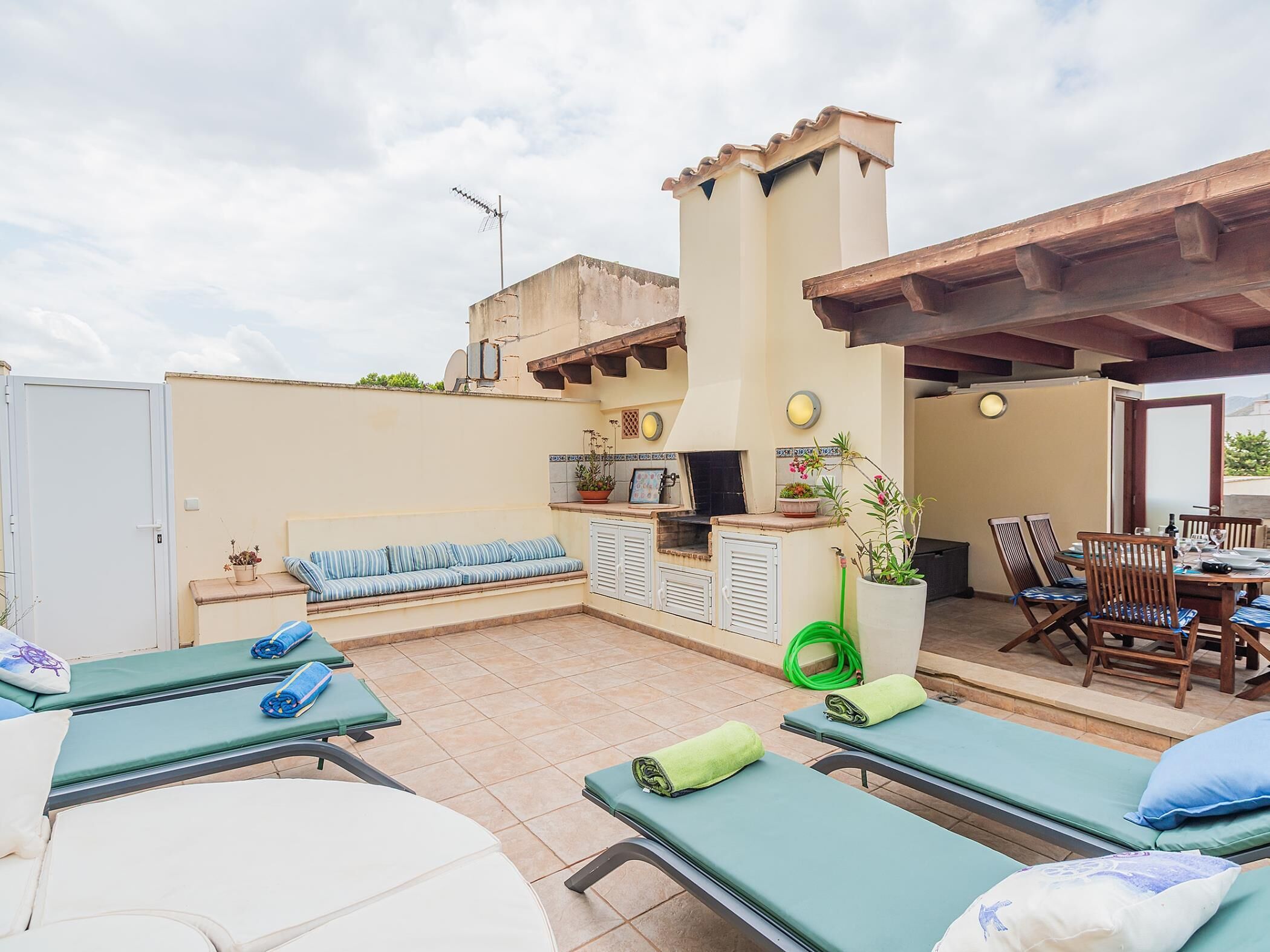 A rooftop terrace with lounge chairs, a barbecue area, and a dining set.