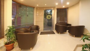 A lobby with brown leather sofas, a potted plant, and a glass door with a wreath.