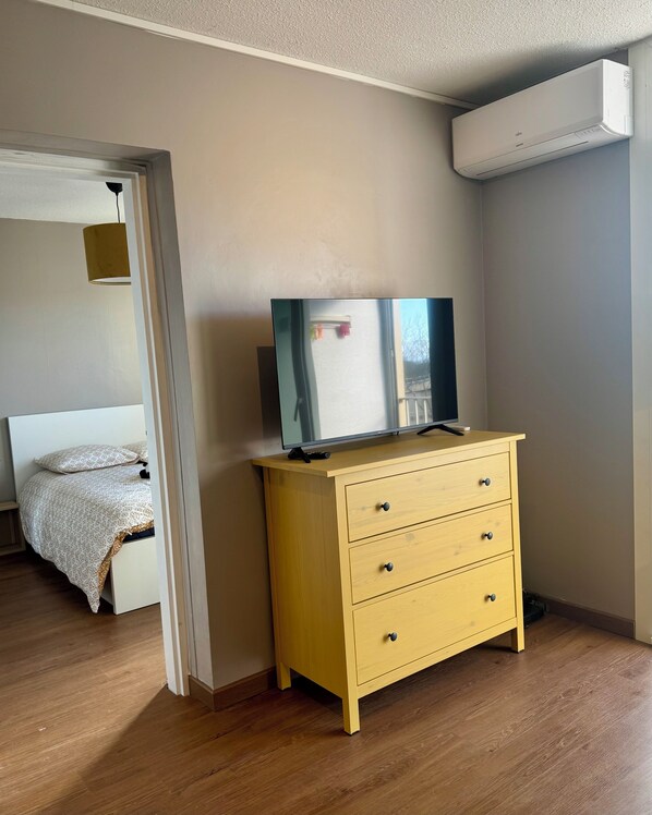 Un dormitorio con una cama, un aparador y un aire acondicionado.