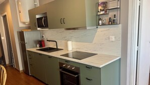 A compact kitchen with a sink, stove, and microwave.