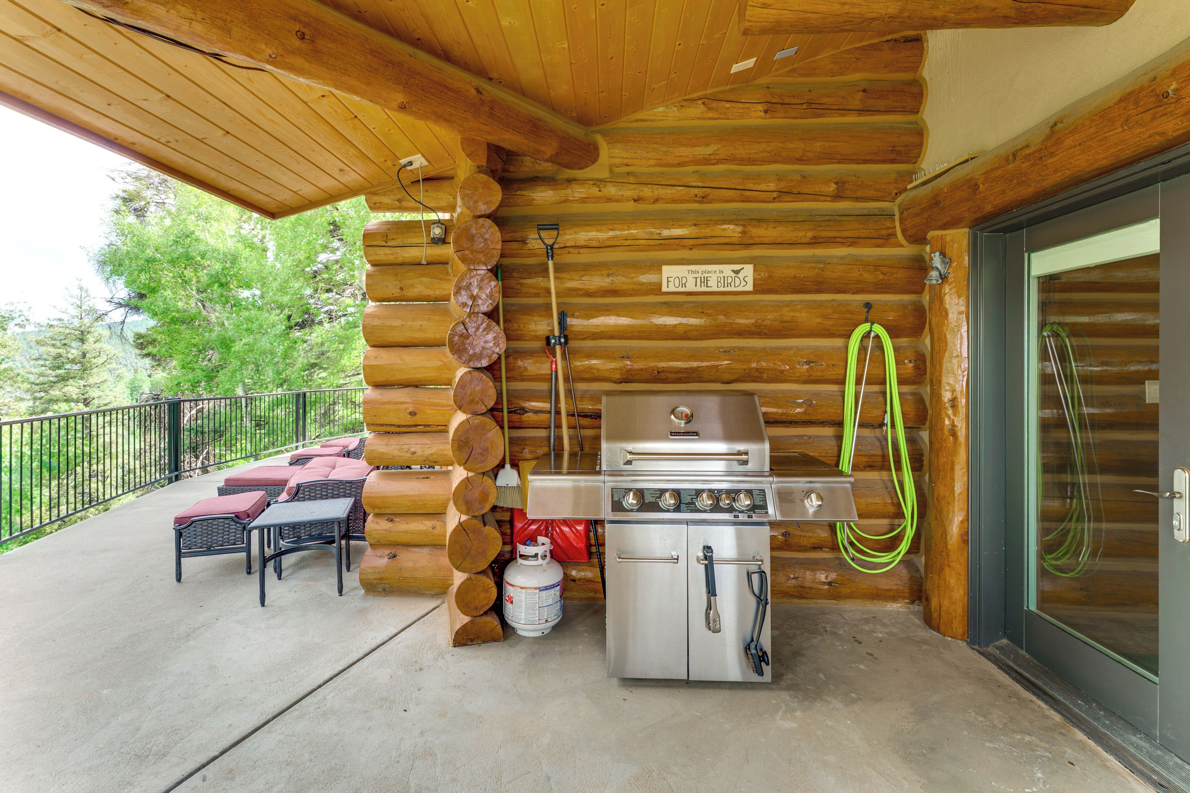 A wooden cabin with a grill, outdoor seating, and a sign indicating it's a bird-friendly place.