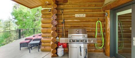 A wooden cabin with a grill, outdoor seating, and a sign indicating it's a bird-friendly place.