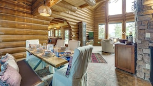 Ein Blockhaus-Interieur mit Essbereich, Kamin und einer Steinwand.
