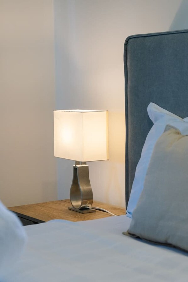 A neatly made bed with a grey headboard, a bedside lamp, and a pillow on the right side. - Spacious Family Retreat in Peaceful Parkinson (Parkinson)
