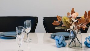 A dining table set with blue plates, clear glasses, and a centerpiece with a vase of flowers and blue decorative items. - Spacious Family Retreat in Peaceful Parkinson (Parkinson)