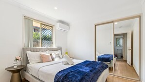 A modern bedroom with a large bed, a bedside table with a vase, a window with a view, and a mirror. - Spacious Family Retreat in Peaceful Parkinson (Parkinson)