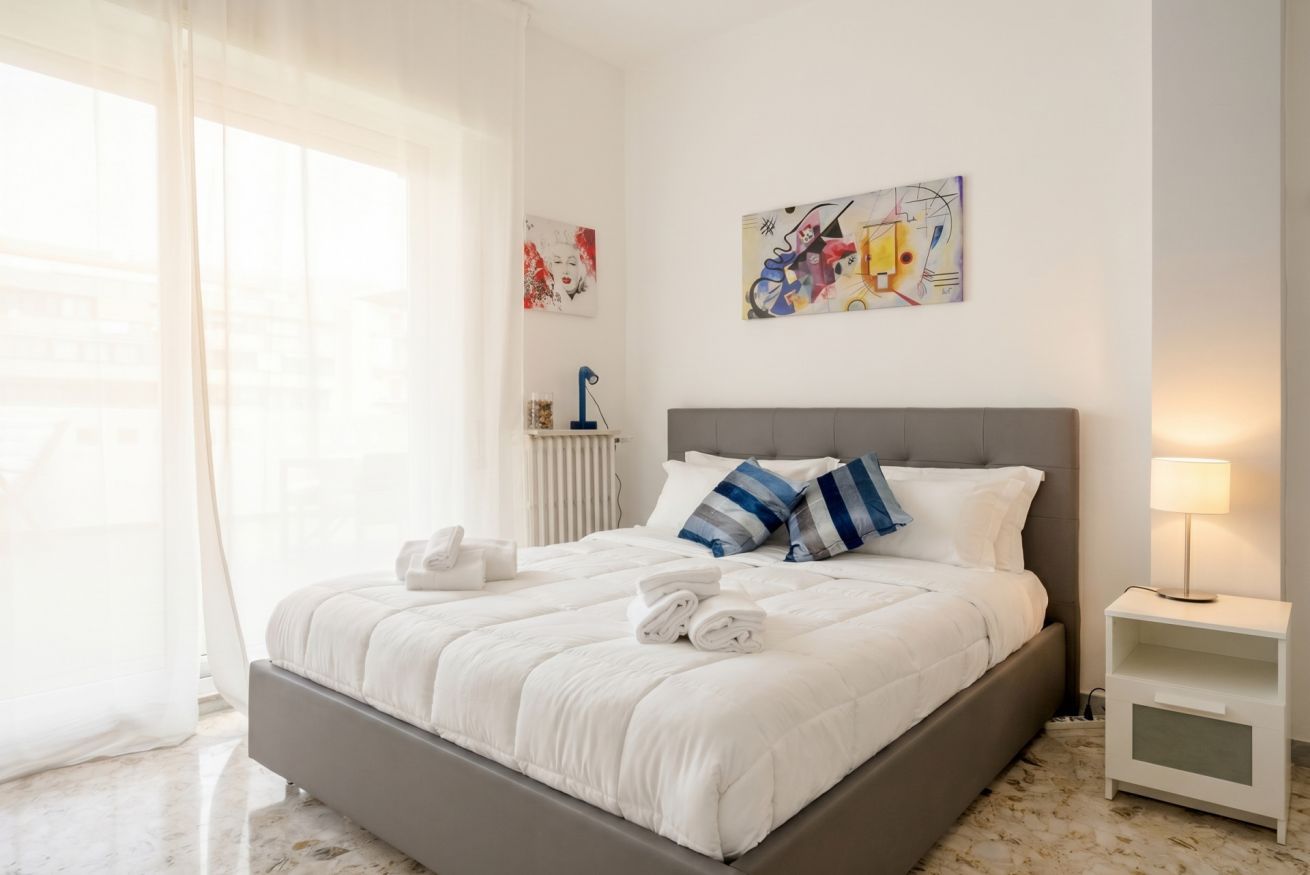 Ein Hotelzimmer mit einem großen Bett, einem Nachttisch, einer Lampe und einem Bild an der Wand.