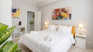 Une chambre d’hôtel avec un grand lit, deux lampes de chevet, un tableau au mur et une petite plante posée sur une étagère.