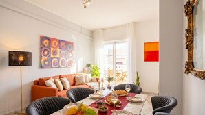 Un coin repas avec une table dressée pour quatre personnes, un canapé, une lampe et un tableau accroché au mur.