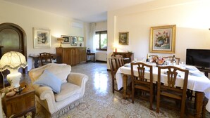 Un coin repas avec une table dressée pour quatre personnes, un canapé, un meuble et un téléviseur.