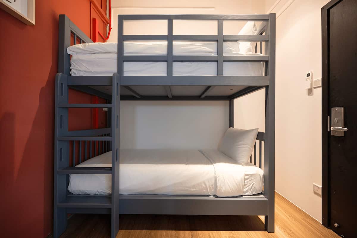 A bunk bed with white bedding and a wooden floor.
