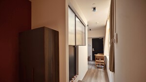 A hallway with a wooden bench, a sliding door, and a small table with chairs. - Hmlet Chinatown (Singapore)