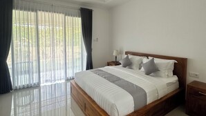 Ein geräumiges Schlafzimmer mit einem großen Bett, einem Nachttisch und einem Fenster mit Vorhängen.