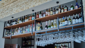 Zona de bar con estanterías llenas de botellas de licor y un porta copas de vino.