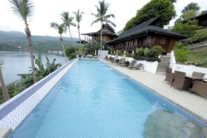 A swimming pool with lounge chairs and a view of a mountain and lake. - Villa De Pico Highland Beach Resort (Puerto Galera)