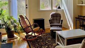 A cozy living room with a high ceiling, wooden flooring, and a large window overlooking a garden. - Whimsical Wildwood Studio – Breakfast Included – Award-Winning Appalachian B&B (Irvine)