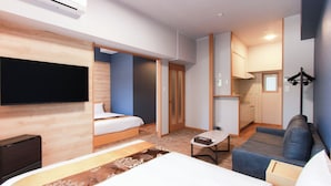 Ett modernt hotellrum med en säng, en soffa, ett litet bord och en tv.