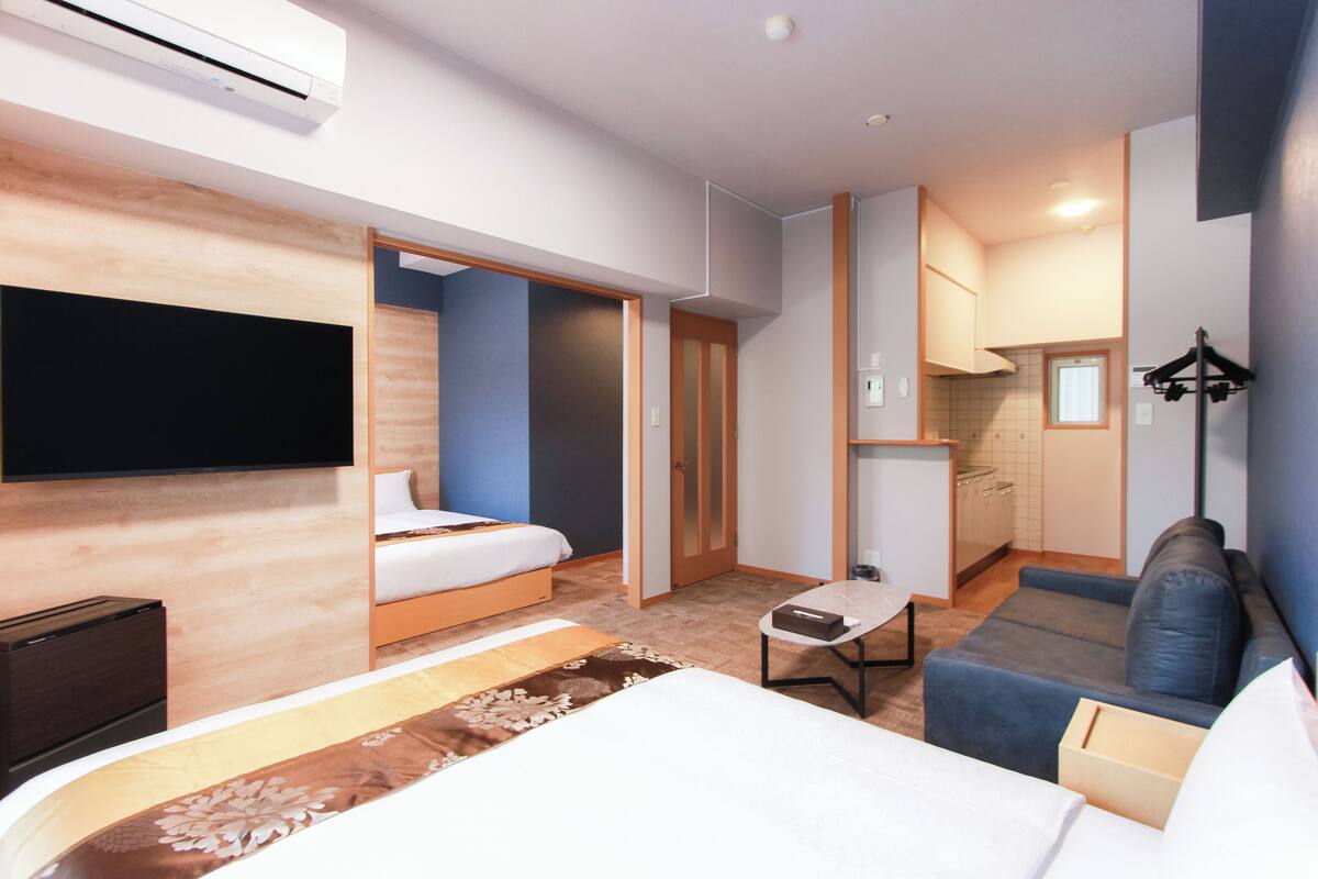 Ein modernes Hotelzimmer mit Bett, einer Couch, einem kleinen Tisch und einem Fernseher.