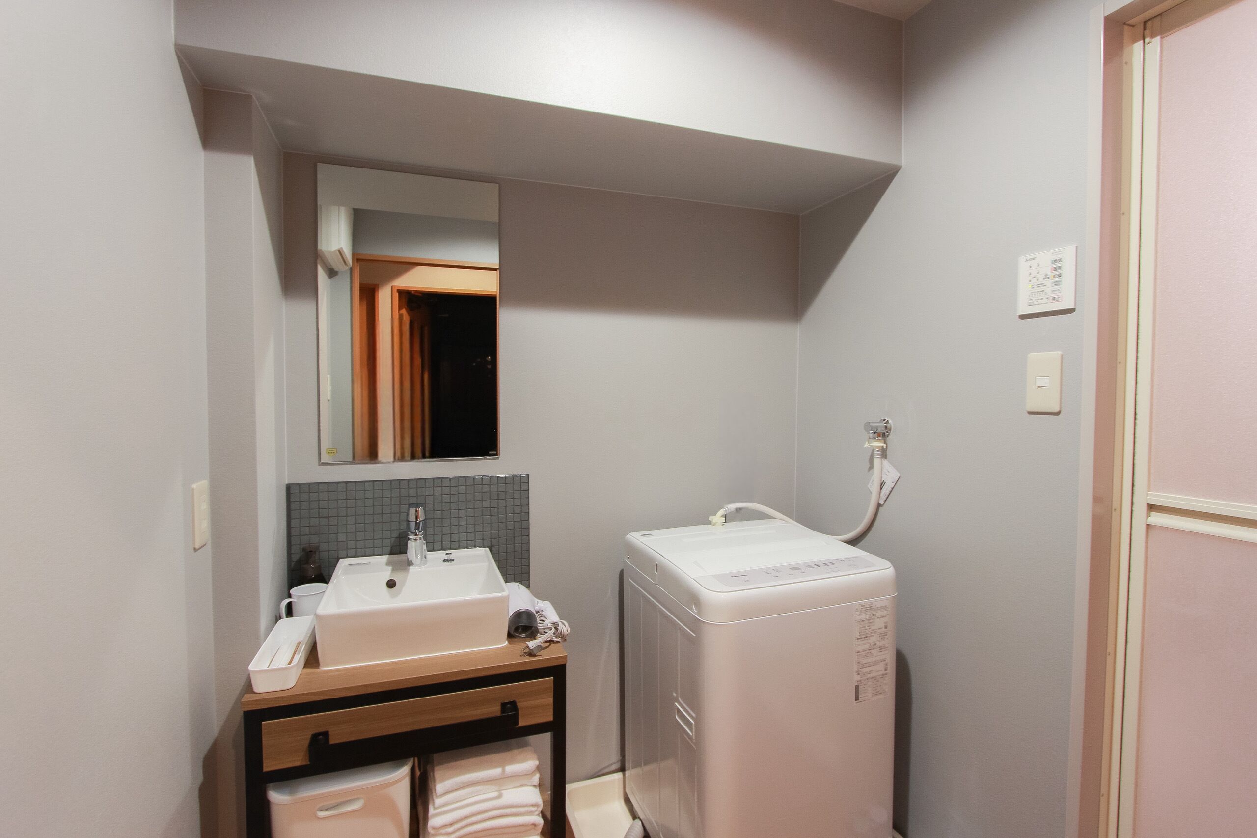 Un baño pequeño con lavamanos, espejo y lavadora-secadora compacta.