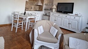 Un espai vital compacte amb zona de menjador, petita cuina i televisió.