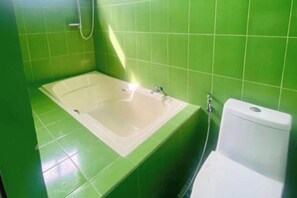 A bathroom with a bathtub, toilet, and green tiled walls. - Catappa Lodge Puerto Galera (Puerto Galera)