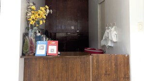 A reception area with a wooden counter, a vase of yellow flowers, and QR codes for payment.