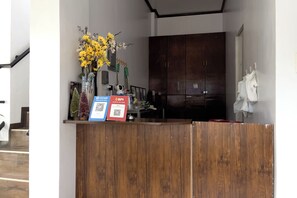 A reception desk with a wooden counter, a vase of yellow flowers, and two QR code payment options. - Catappa Lodge Puerto Galera (Puerto Galera)