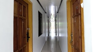A hallway with wooden doors on either side, a light-colored floor, and a ceiling light fixture.