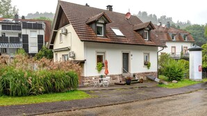 A two-story house with a sloped roof, a front porch with a table and chairs, and a small garden area. - Holiday Home 'Marina' with Private Terrace, Wi-Fi and Air Conditioning (Baden-Baden)