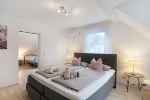 Une chambre à coucher avec un grand lit, des lampes de chevet, une petite table et une fenêtre avec des rideaux.