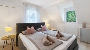 A bedroom with two beds, a window with a view, a lamp, and a radiator. - Holiday Home 'Marina' with Private Terrace, Wi-Fi and Air Conditioning (Baden-Baden)